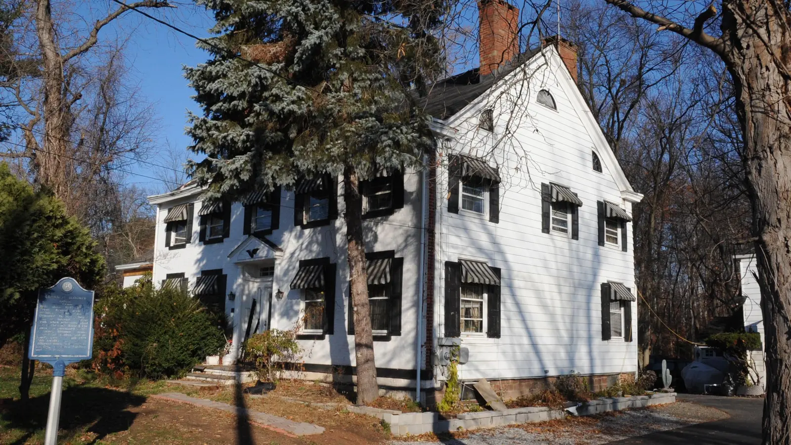 Two-story colonial-style house framed by mature trees.